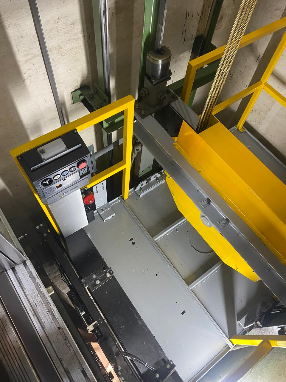 Upgraded car top with a yellow handrail balustrade, red buffer, no-standing plates, marked safe refuge space decal and a yellow inspection control station.