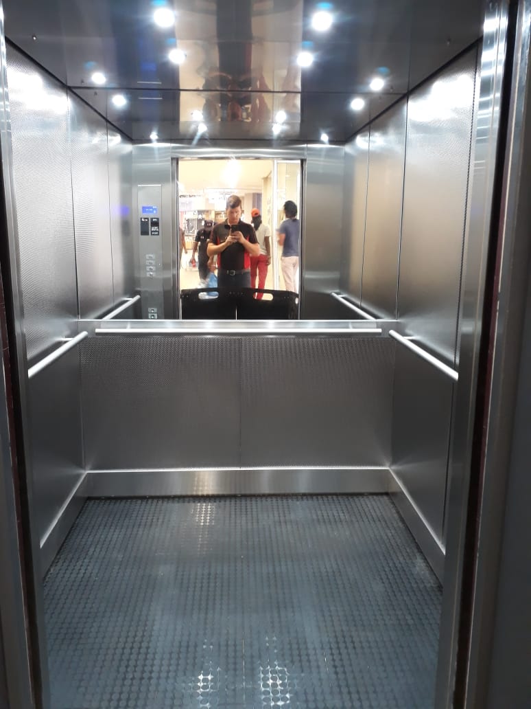 Patterned stainless steel lift cab with mirrored ceiling, downlights, stainless handrails and studded rubber flooring.